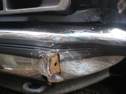 1993 Ford Bronco - Close-up view of a damaged front bumper, showing rust and impact marks.