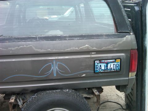 1986 Ford Bronco - The rear of a gray Ford Bronco shows pinstriping and a custom license plate.