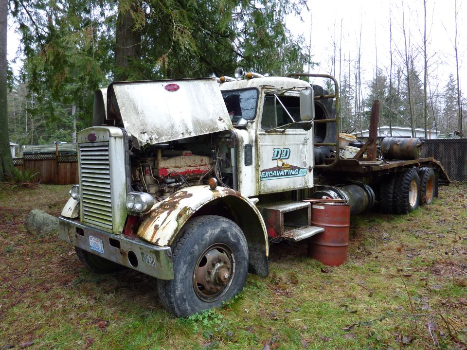 Weathered white Peterbilt semi truck with hood open showing diesel engine