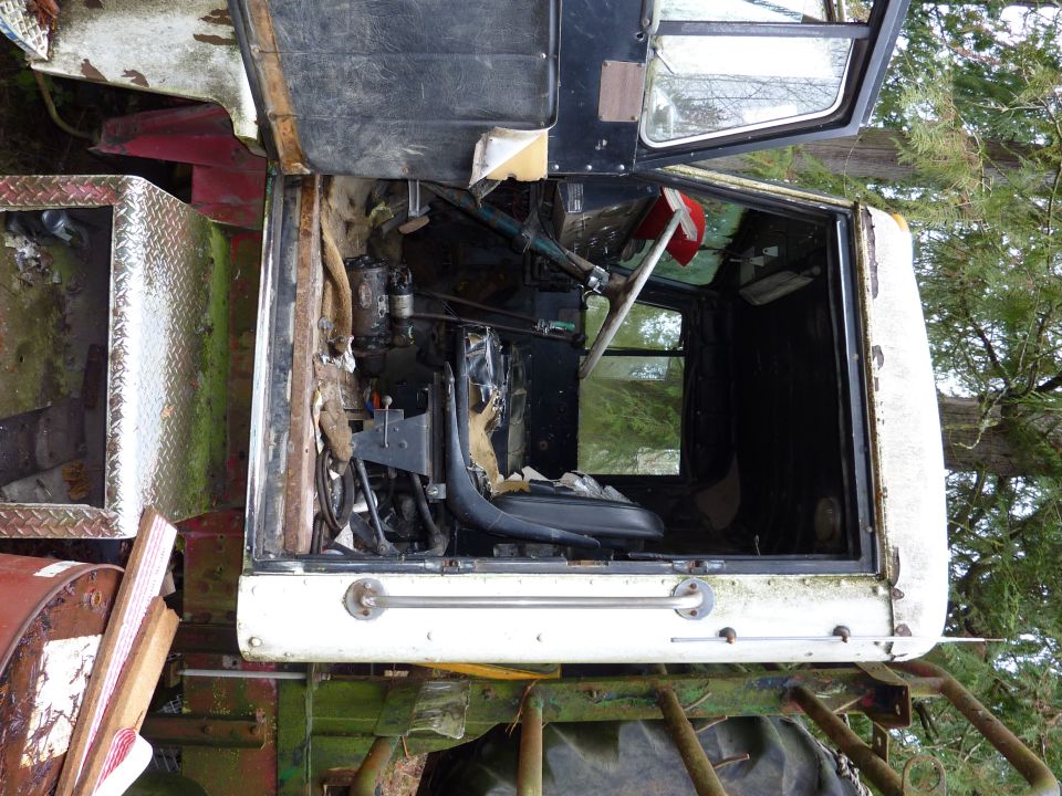 Interior of a dilapidated truck cab, showing torn seats and exposed wiring