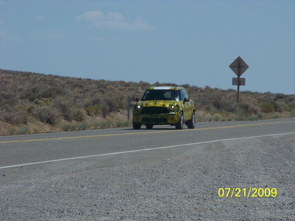 Yellow Mini Countryman prototype on a highway, covered in camouflage wrap