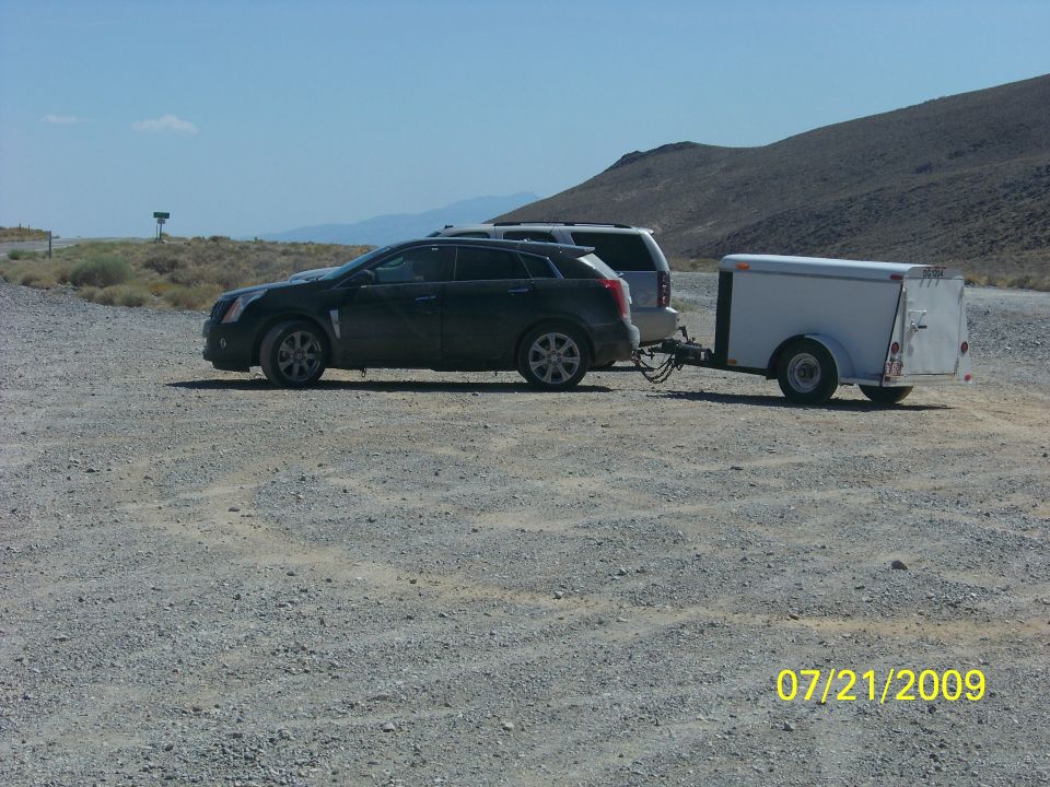 Dark SUV towing a white trailer on a gravel road