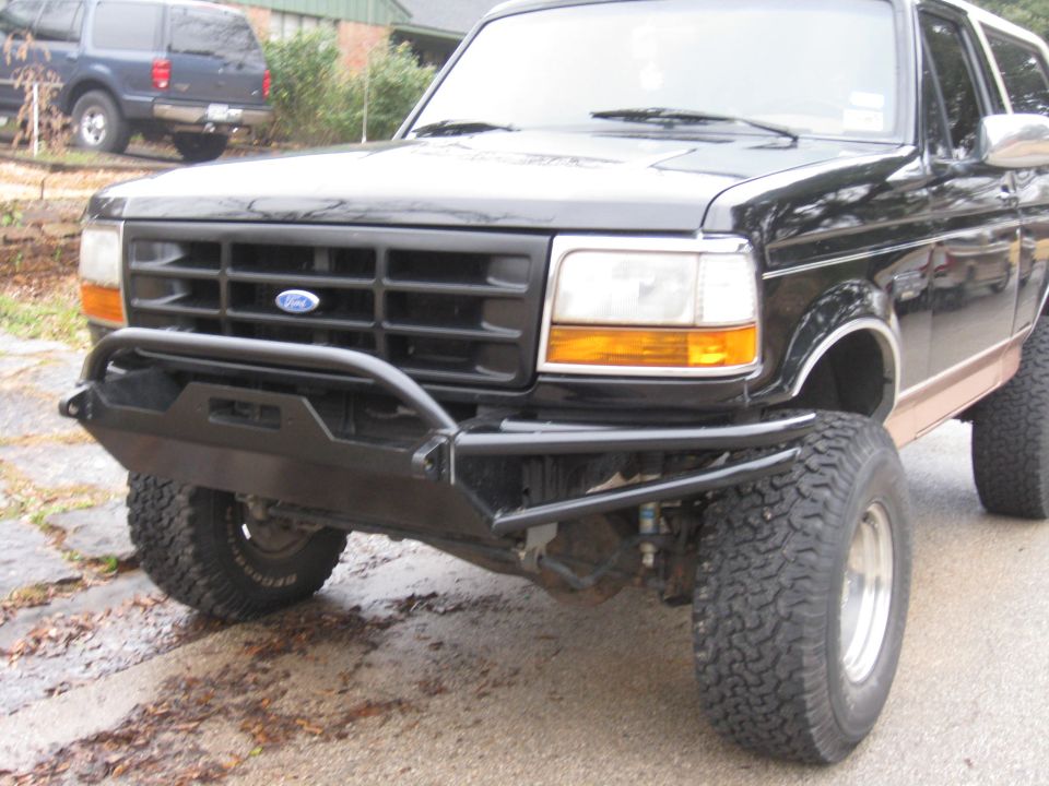 Black Ford Bronco with black tubular front bumper on a wet driveway.