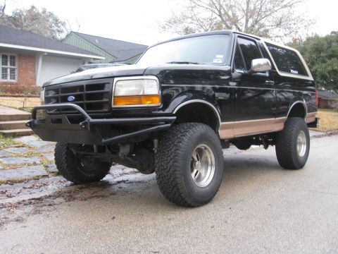 1994 Ford Bronco - This lifted black Ford Bronco features a custom front bumper and tan body trim.