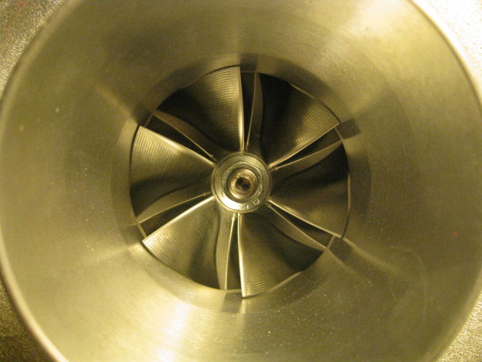 Close-up of a turbocharger compressor wheel with curved blades