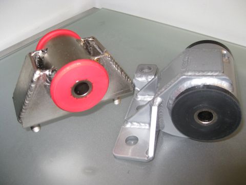1994 Ford Probe - Two engine mounts, one with red bushings and one with black bushings, are displayed on a flat surface.