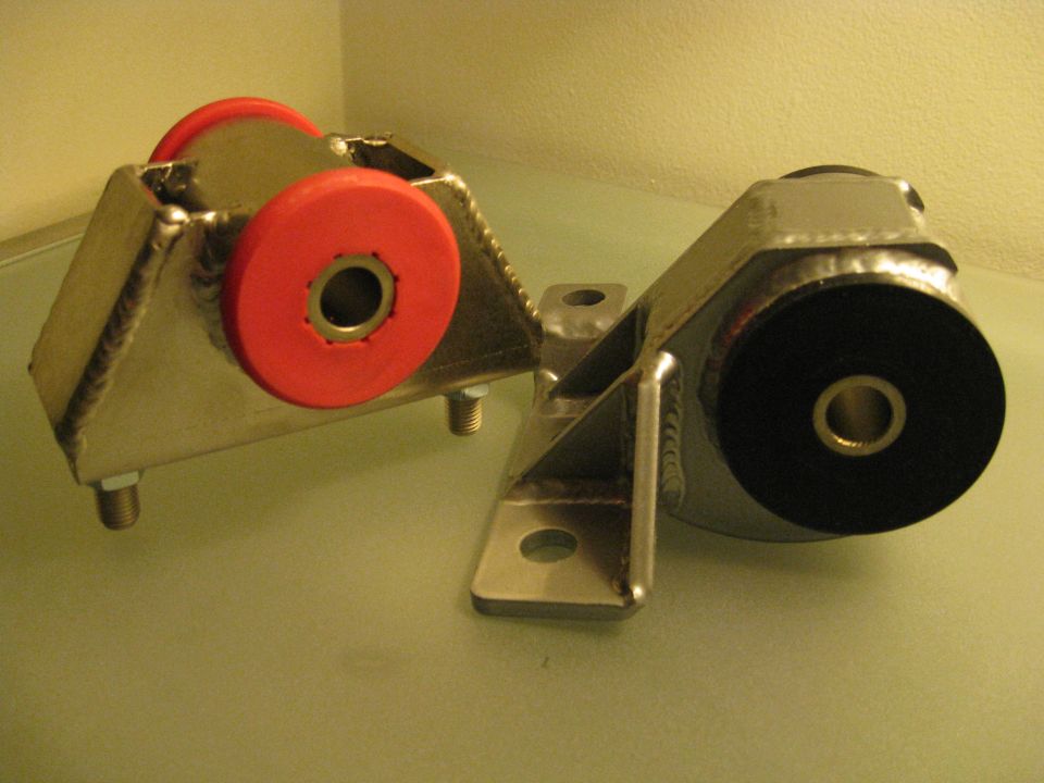 Two aftermarket engine mounts, one with red bushings, one with black