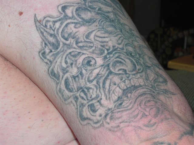 Tattoo of a demon face on a person's arm