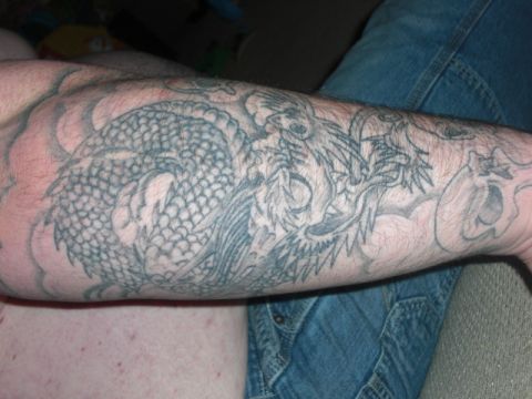 1994 Ford Bronco - A detailed dragon tattoo covers a person's arm, with blue jeans in the background.