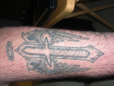 1994 Ford Bronco - Close-up of a tattoo a cross with wings and a halo on a person's arm.