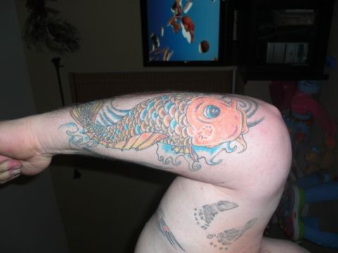 1994 Ford Bronco - A colorful koi fish tattoo is inked on an arm, with a television screen displaying an image in the background.