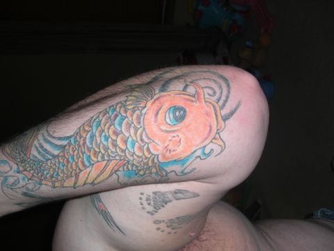 1994 Ford Bronco - A colorful koi fish tattoo covers the arm and extends onto the torso, with other tattoos visible below.