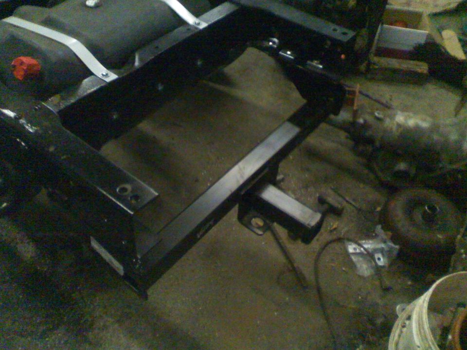 Trailer hitch assembly mounted on a vehicle frame, with a fuel tank visible