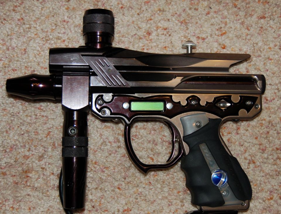 Polished electronic paintball marker with green LCD and milled body on beige carpet