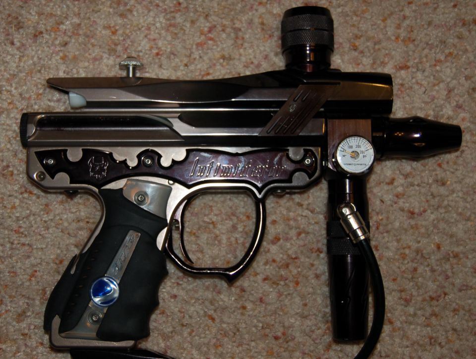 Chrome and black paintball marker with regulator and gauge on carpet