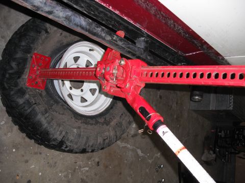 1991 Ford Bronco - A red hi-lift jack is shown lifting a tire and wheel, likely for off-road use.