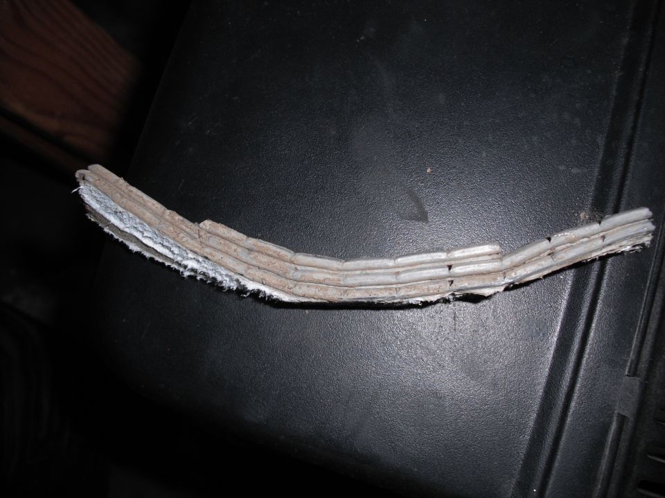 Strip of old wheel weights, some detached, on a dark surface