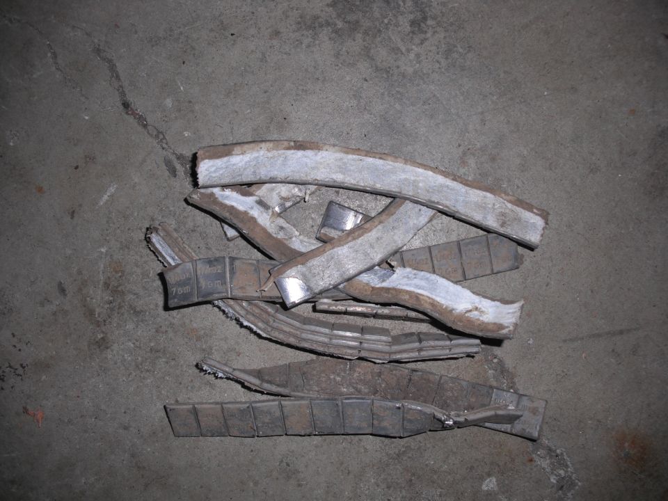 Scattered wheel weights on concrete floor, some with visible 70gm markings