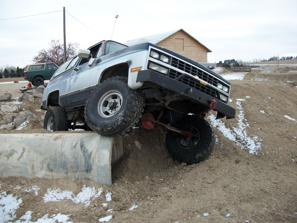 off-road SUV climbing over concrete barrier, another SUV in background