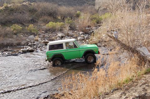 1996 Ford Bronco - This green Ford Bronco with a white top navigates a rocky stream bed.
