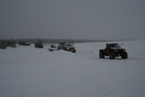1987 Suzuki Samurai - Multiple off-road vehicles navigate a snow-covered landscape on an overcast day.
