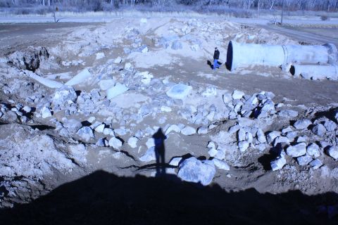 1989 Ford Bronco - A scene of a construction site large concrete pipes and scattered rocks, with two figures visible for scale.