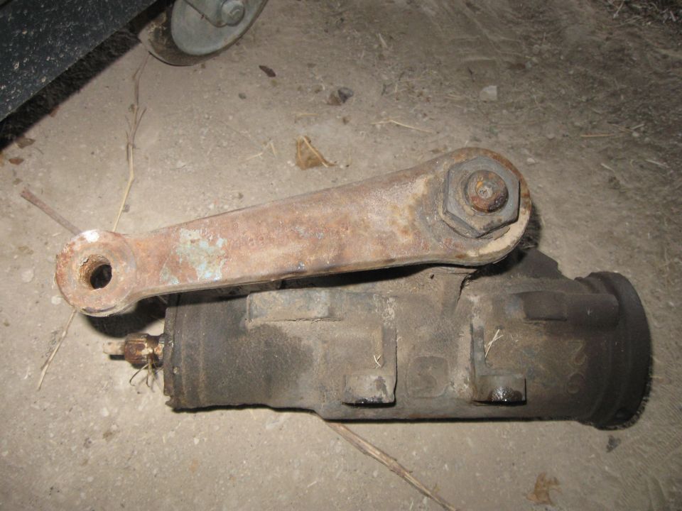 Rusty steering rack with attached tie rod, lying on concrete