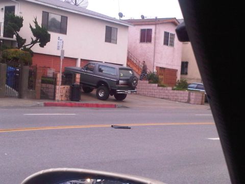 1986 Ford Bronco - This SUV is parked on a very steep street, with its spare tire mounted on the rear door.
