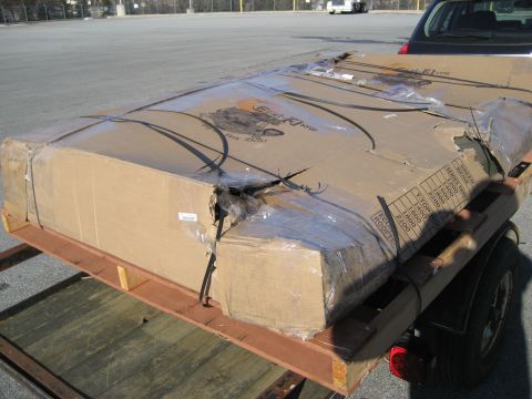 1996 Ford Bronco - A large, damaged cardboard box is secured to a trailer, ready for transport.