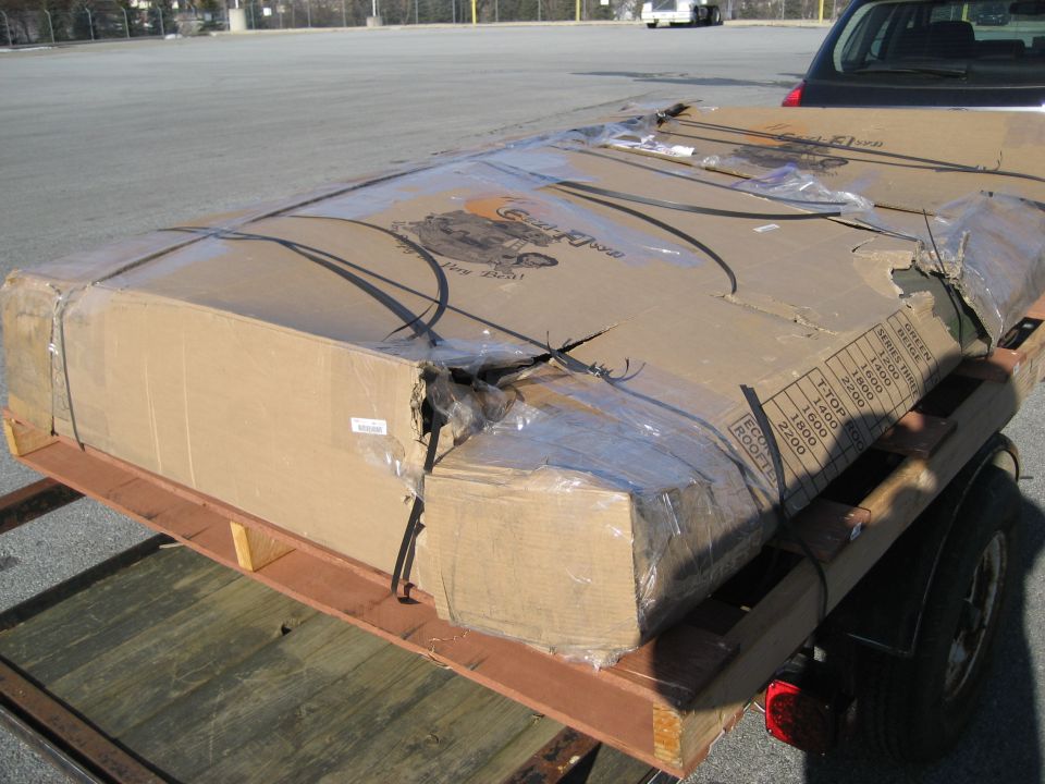 large cardboard box on trailer, some damage to packaging