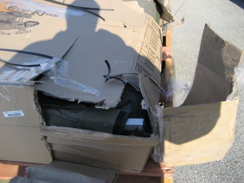 1996 Ford Bronco - A damaged cardboard box reveals a green tent and metal poles, suggesting it contains camping equipment.