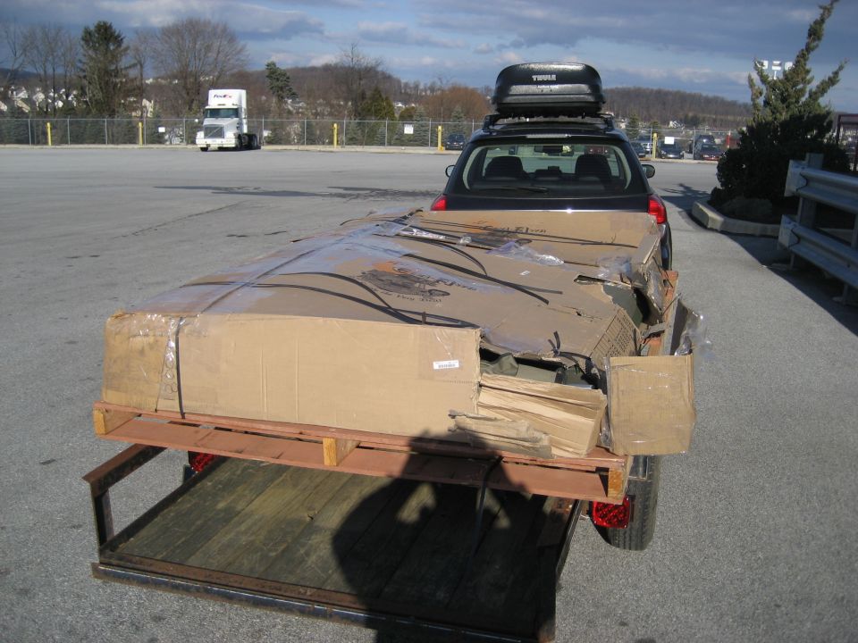 car with roof box towing trailer loaded with large cardboard boxes