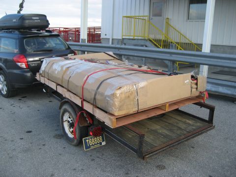 1996 Ford Bronco - A dark SUV tows a trailer carrying a large, securely strapped package.
