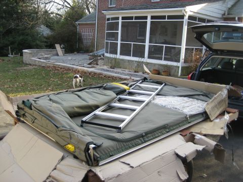 1996 Ford Bronco - A tent and ladder are placed in the open trunk of a car, with a house and yard in the background.