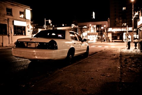 2003 Ford Crown Victoria - A white 2003 Ford Crown Victoria is parked on a street at night, with buildings and streetlights in the background.