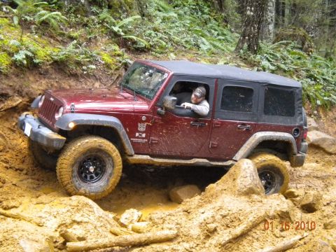2005 Jeep Wrangler - A maroon 2005 Jeep Wrangler tackles a challenging muddy terrain on an off-road adventure.