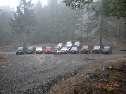 2005 Jeep Wrangler - A group of Jeep Wranglers and other SUVs are parked in a gravel lot on a foggy day.