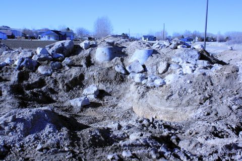 1989 Ford Bronco - A construction site features large rocks and concrete pipes under a clear blue sky.