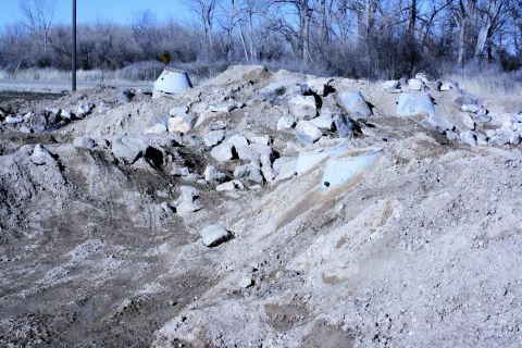 1989 Ford Bronco - A scene of construction debris with tire tracks in the dirt, no vehicles are visible.