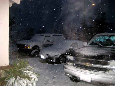 1996 Ford Bronco - Snow falls heavily at night, blanketing three parked vehicles.