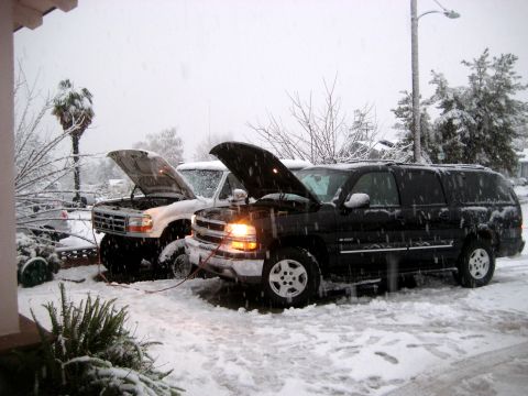1996 Ford Bronco - Two SUVs are parked in the snow with their hoods open, possibly jump-starting.