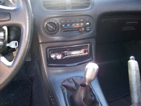1989 Ford Bronco - The interior of a car shows an aftermarket stereo system and a manual transmission shifter with a leather boot.