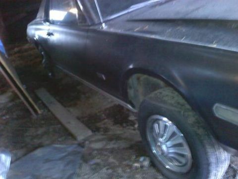 1968 Mercury Cougar - A dark colored car is parked inside a cluttered garage or shed.