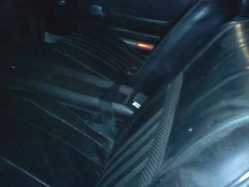 Back seat and part of the driver's seat in a car. There's a Supermotors logo in the corner