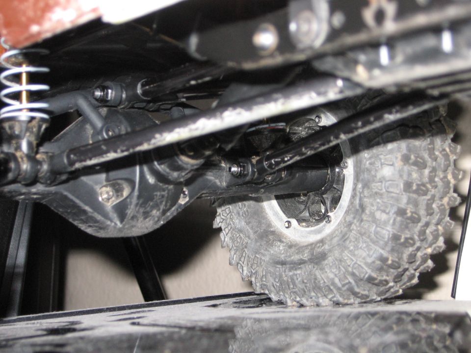 Undercarriage of a vehicle showing suspension, drive shaft, and tire