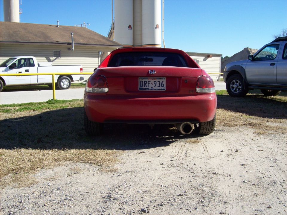 Red Honda Del Sol parked outside with a white pickup truck and a silver SUV nearby
