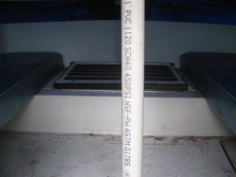 Interior of a boat with blue seats and a white pipe with text on it
