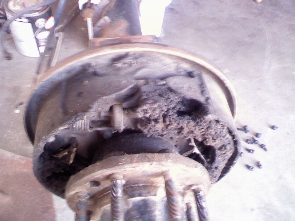 Close-up of a heavily corroded brake drum and hub assembly with visible studs