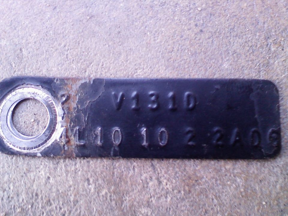 Close-up of a black metal tag with stamped numbers and letters, showing V1310 and L10 10 2 2A06