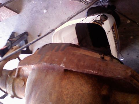 1996 Ford Bronco - Close-up of a rusty rear axle and differential, with a white plastic bucket in the background.